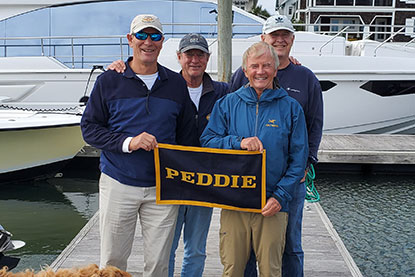 Men stand on a dock and hold a Peddie sign. Links to Over Age 65